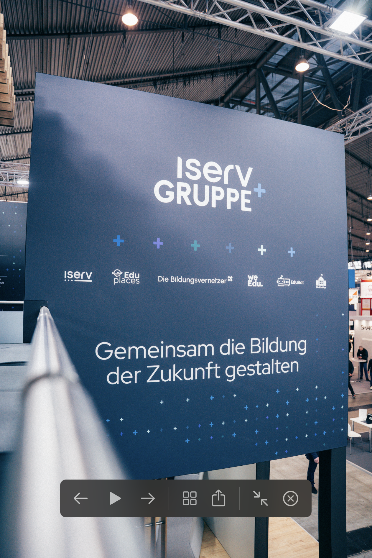 Großformatiges Messeplaket der IServ Gruppe mit Claim "Gemeinsam die Bildung der Zukunft gestalten" und Logos der Partnerunternehmen in moderner blauer Designsprache