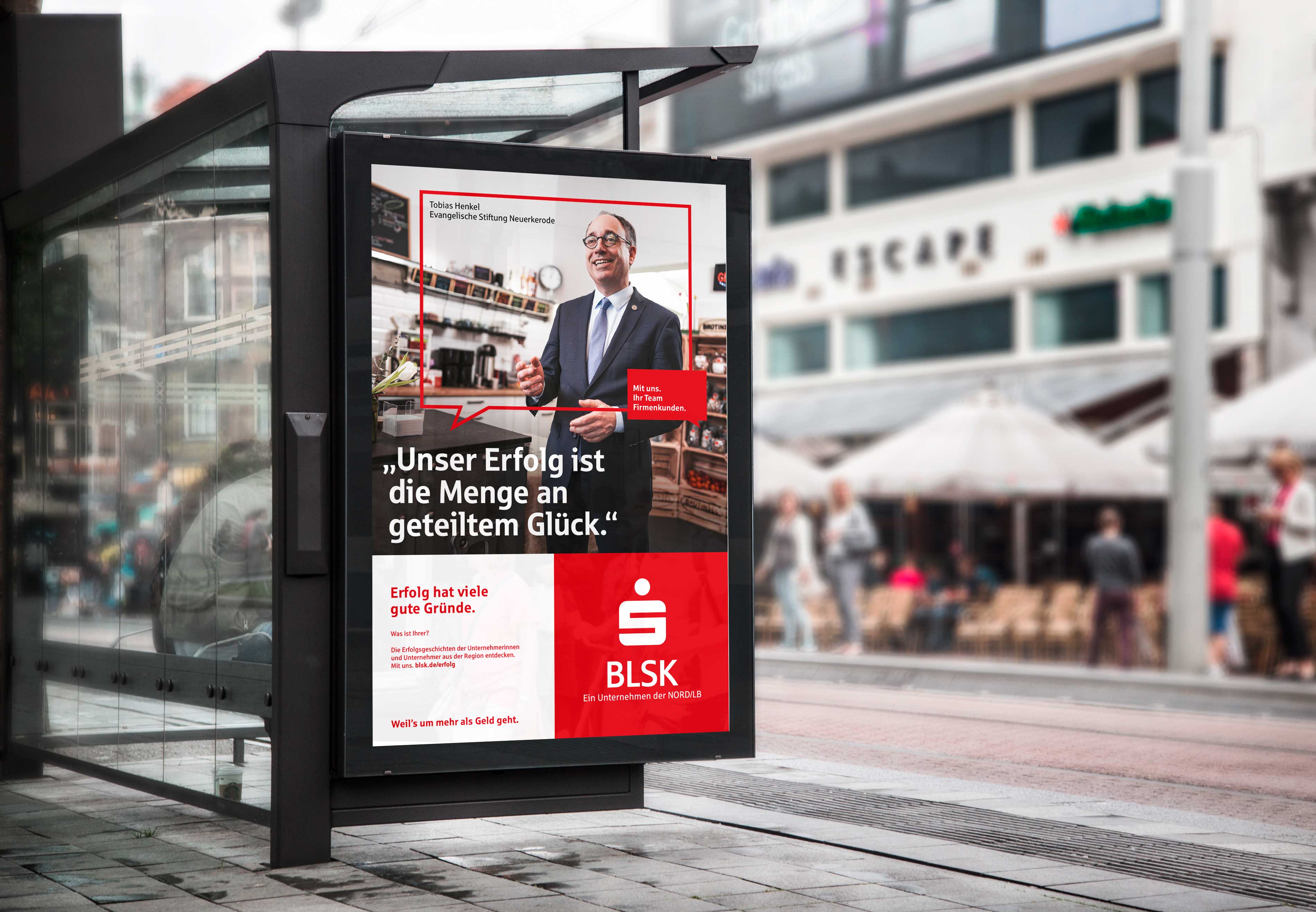Bushaltestelle mit Werbeplakat der Braunschweigischen Landessparkasse BLSK. Kampagne "Erfolg hat viele Gründe" mit Portrait eines Geschäftsführers und Unternehmenslogo auf rotem Hintergrund.