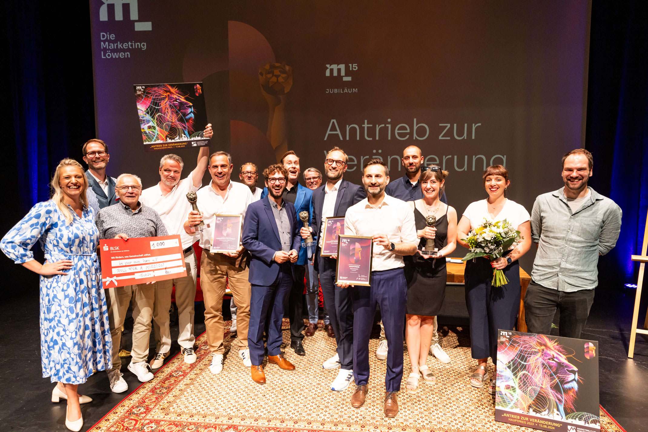 Gewinner der Marketing Löwen Preisverleihung mit Trophäen und Urkunden auf der Bühne zur 15-Jahr-Jubiläumsfeier.